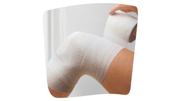 Imagen de una mano vendando una rodilla con una venda cohesiva. Imagen de una mano vendando una rodilla con una venda cohesiva.